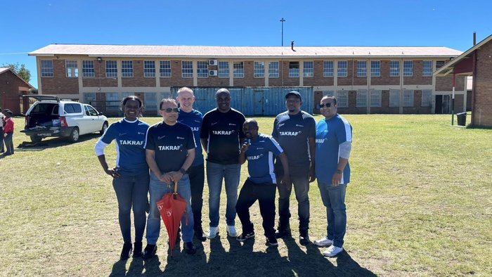 The pictures shows colleagues from the TAKRAF South Africa office supporting the initiative as well as some children wearing the soccer kits on site.