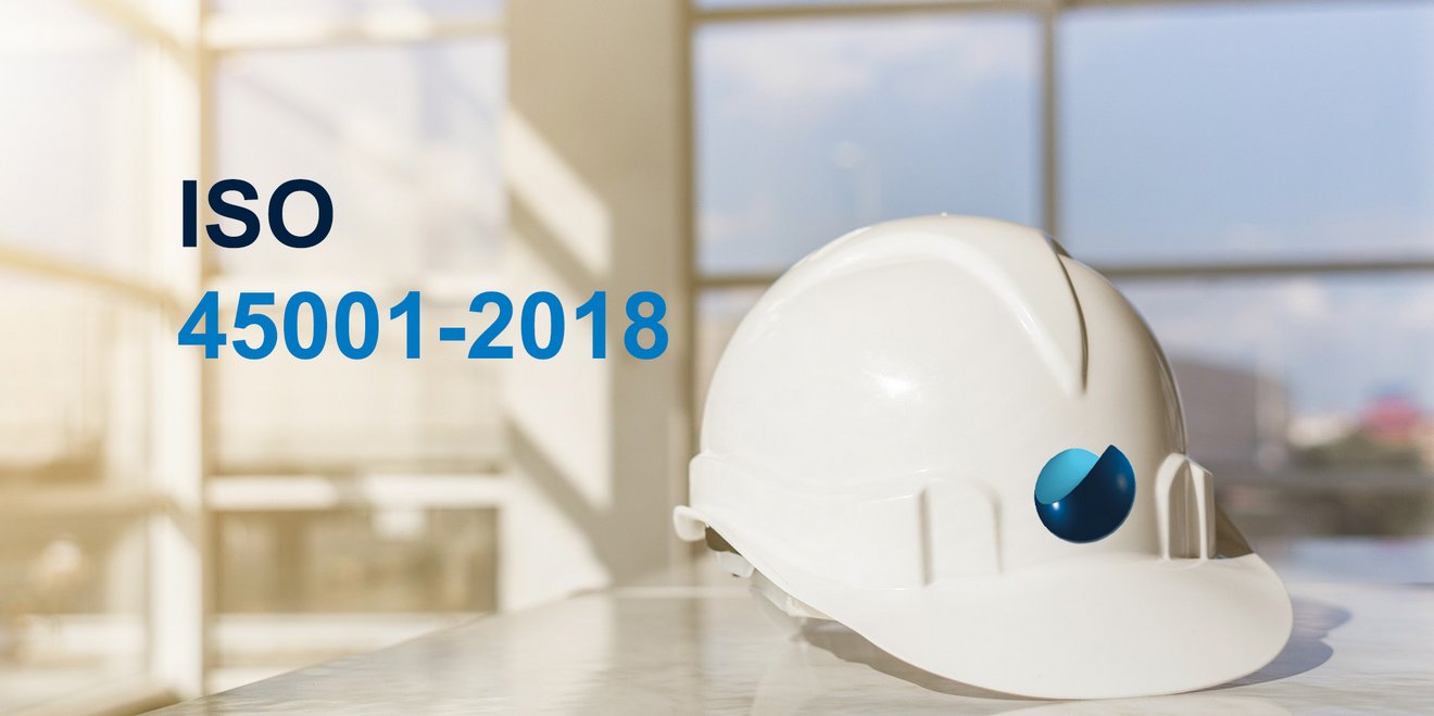 White safety helmet with the TAKRAF logo on a table, writing ISO 45001 - 2018 in front