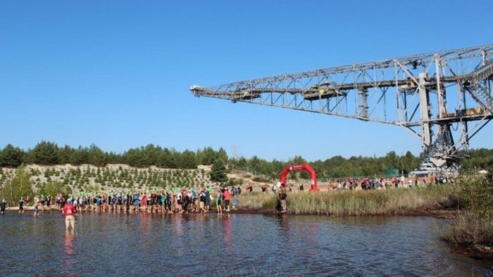 Participants of the triathlon stand at the border of the Bergheider See waiting for the start signal 